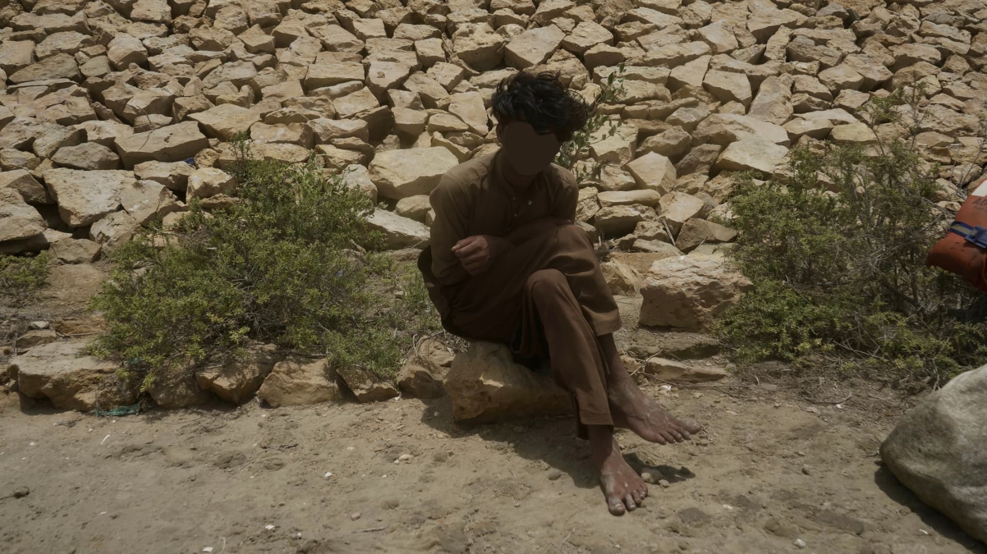 A young fisherman sitting on rocks near the border